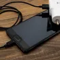 A phone on a table with its charger and cable.